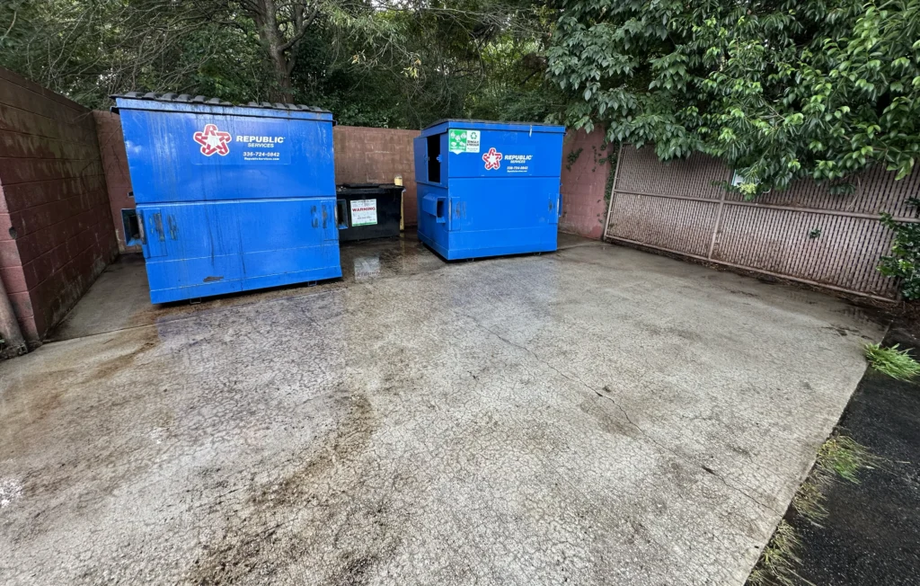 Recently cleaned and sanitized dumpster pad with multiple containers
